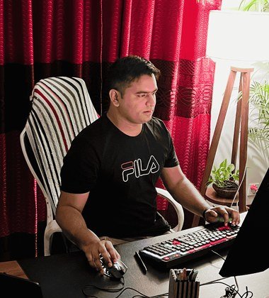 Engr Mejba Ahmed at his desk, working at a keyboard and monitor.